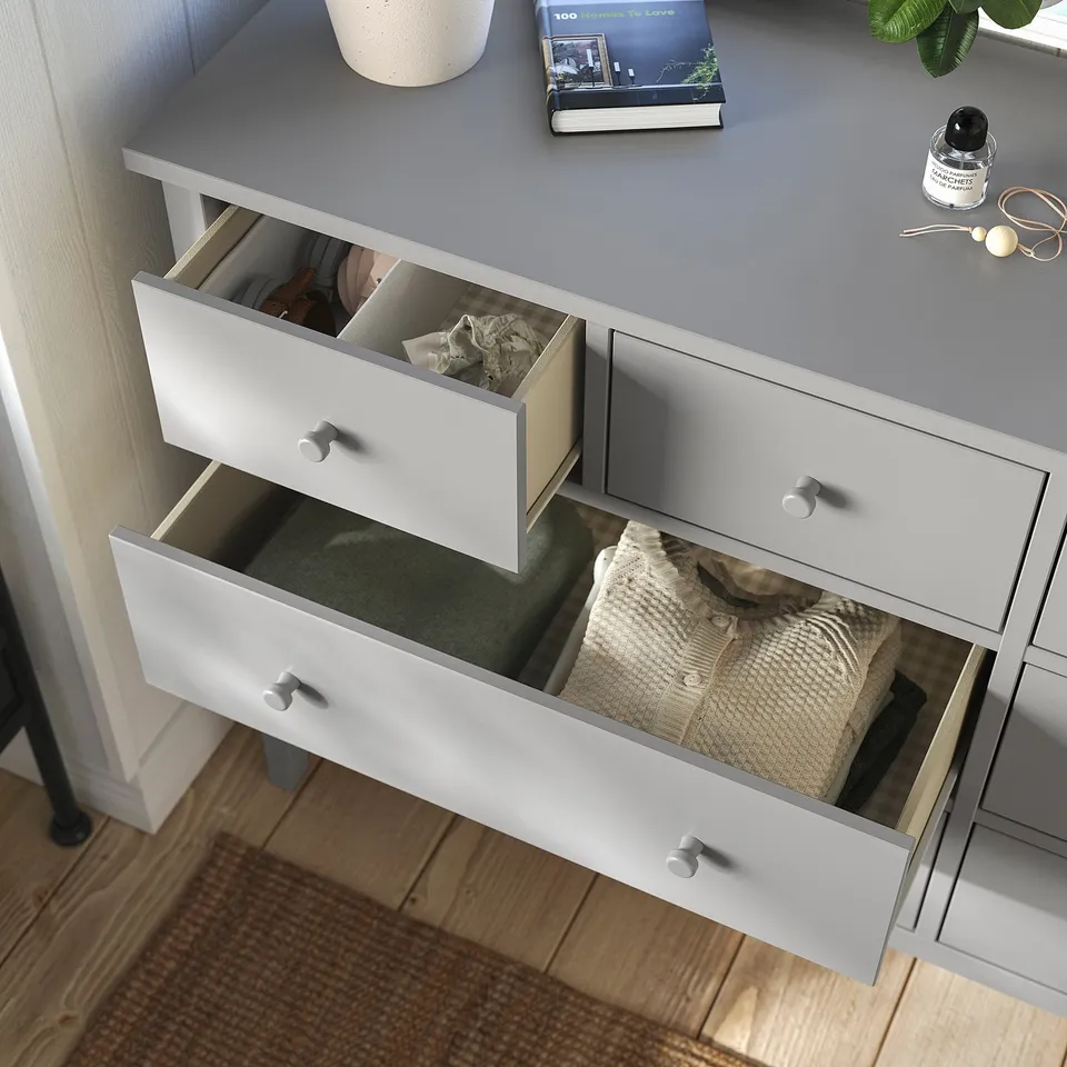 White chest of drawers with three open drawers showing clothing and items inside.