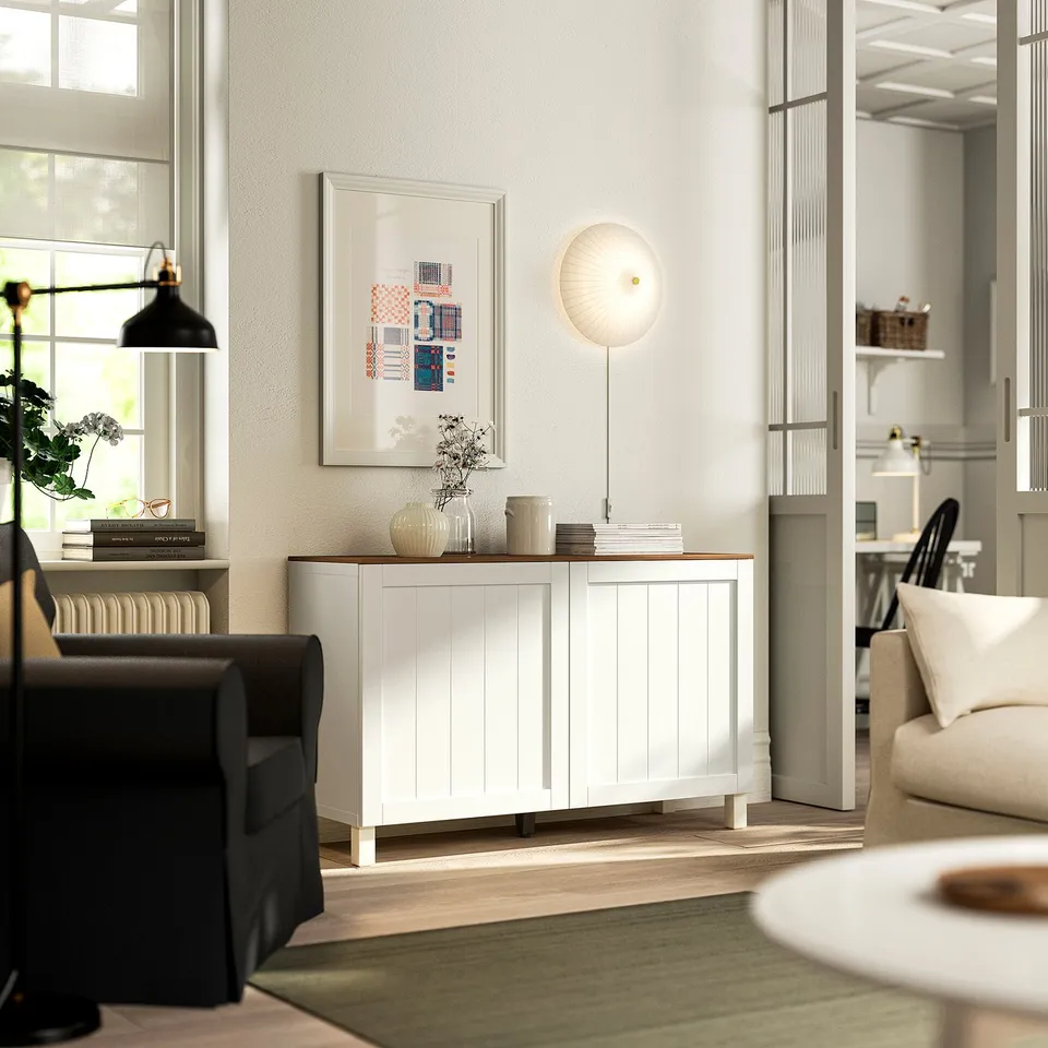 Modern living room with white BESTÅ sideboard, black sofa, green rug, and art.