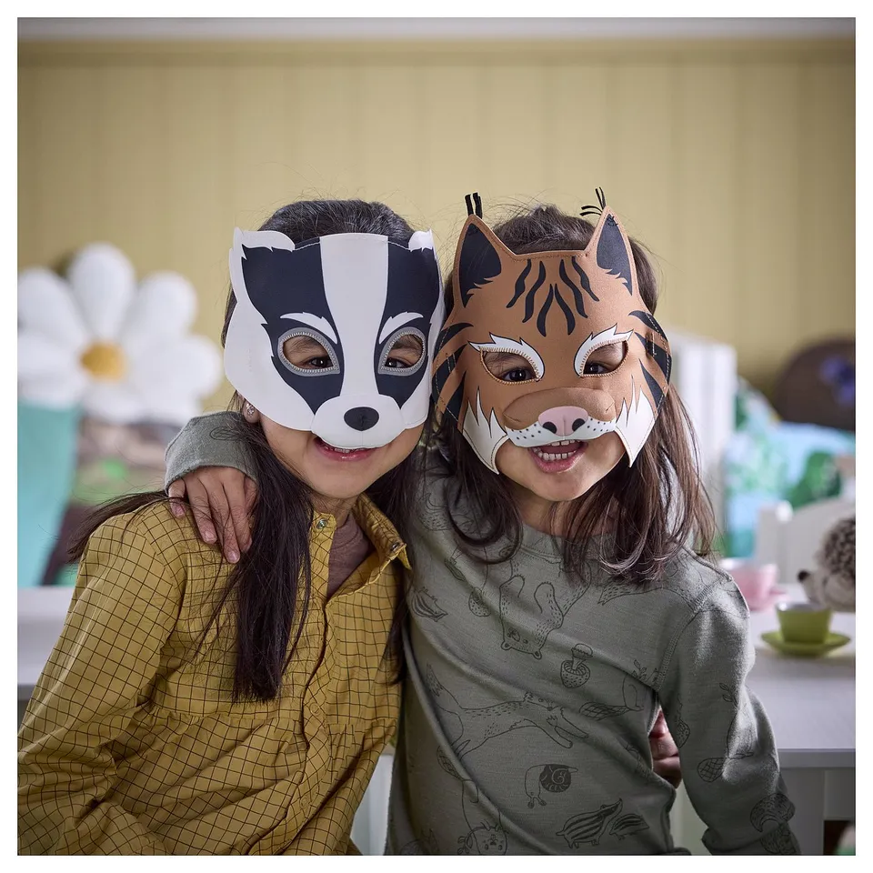 Two girls wearing badger and lynx masks pose together. High-quality, soft masks with secure fastenings, perfect for pretend play.