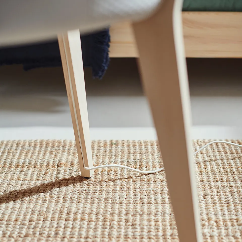 Modern beige woven rug under white table with gold legs.