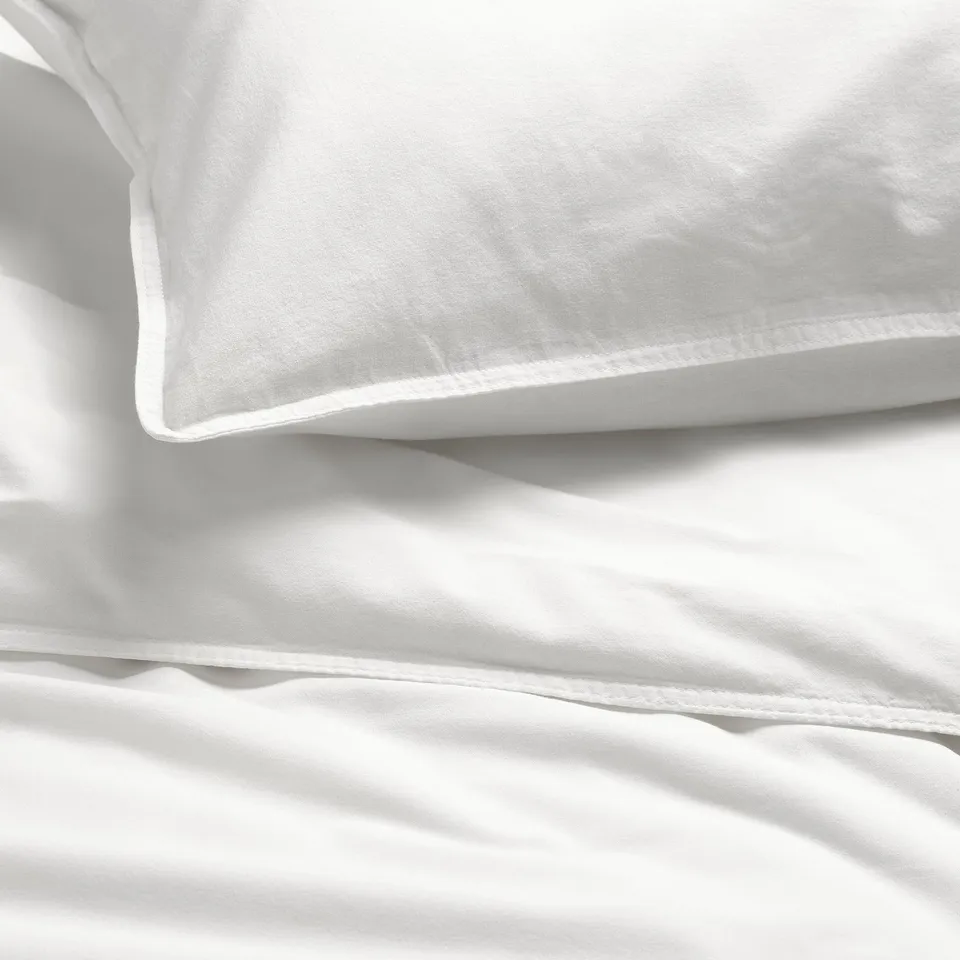 Soft, plush white bedding with smooth lines, showcasing high-quality cotton texture.