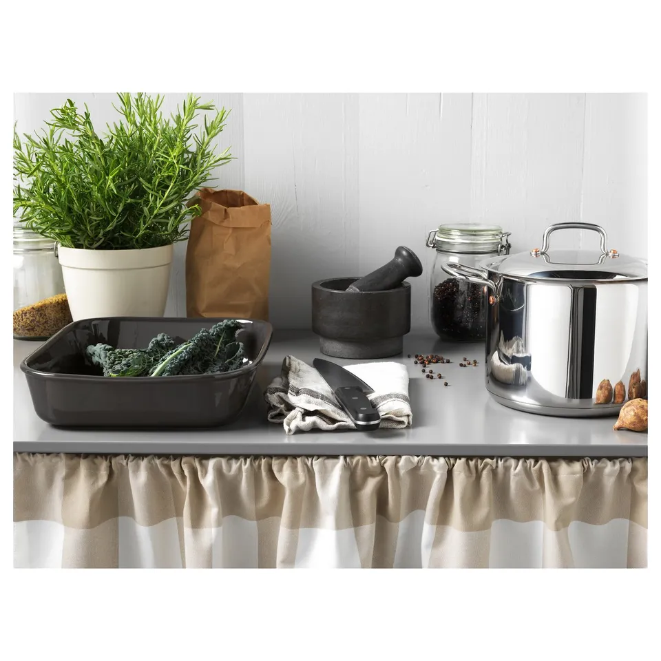 Kitchen scene: grey mortar, pots, veggies, spices, beige curtains.