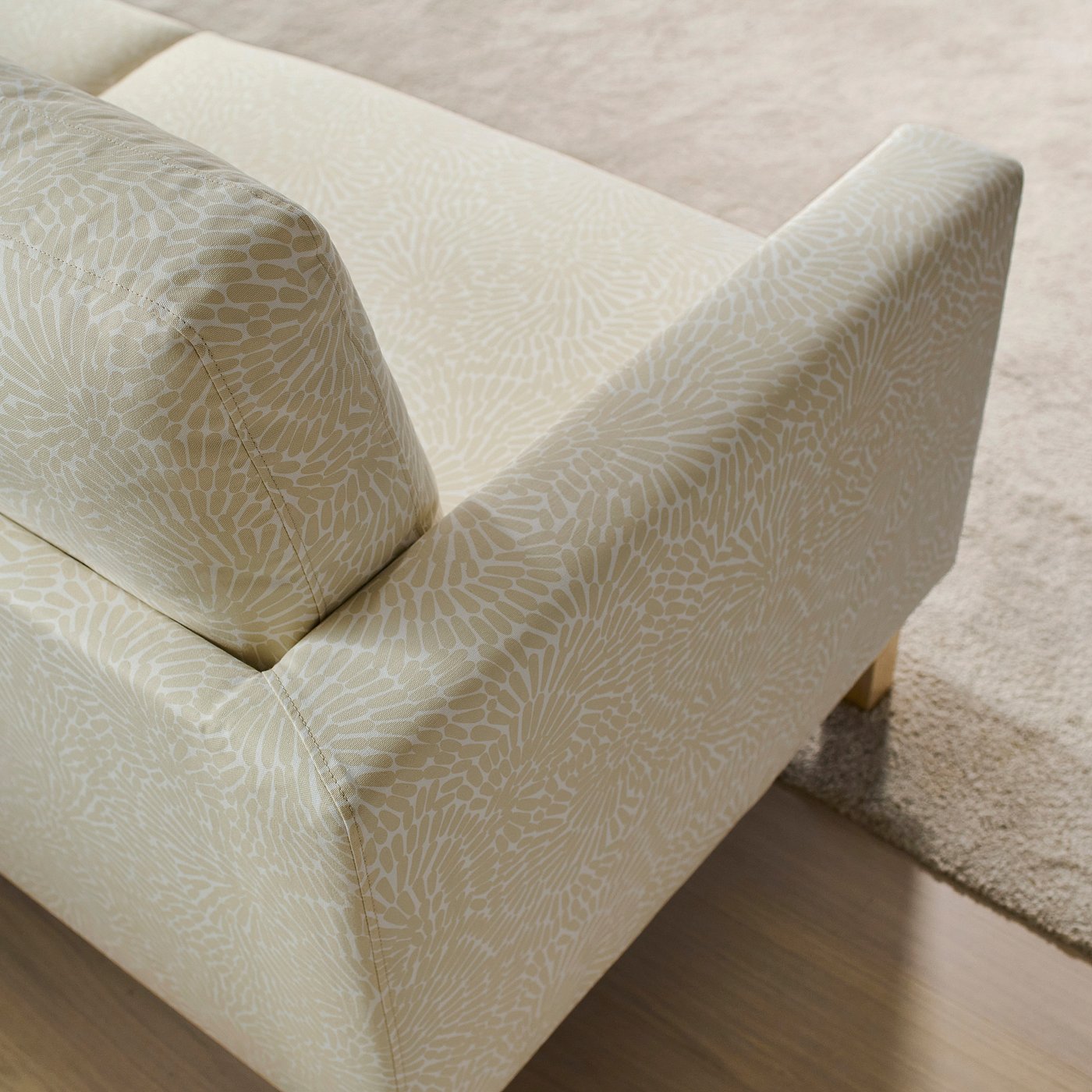 Beige sofa with intricate floral pattern, sturdy construction, soft cushions, and elegant gold legs.