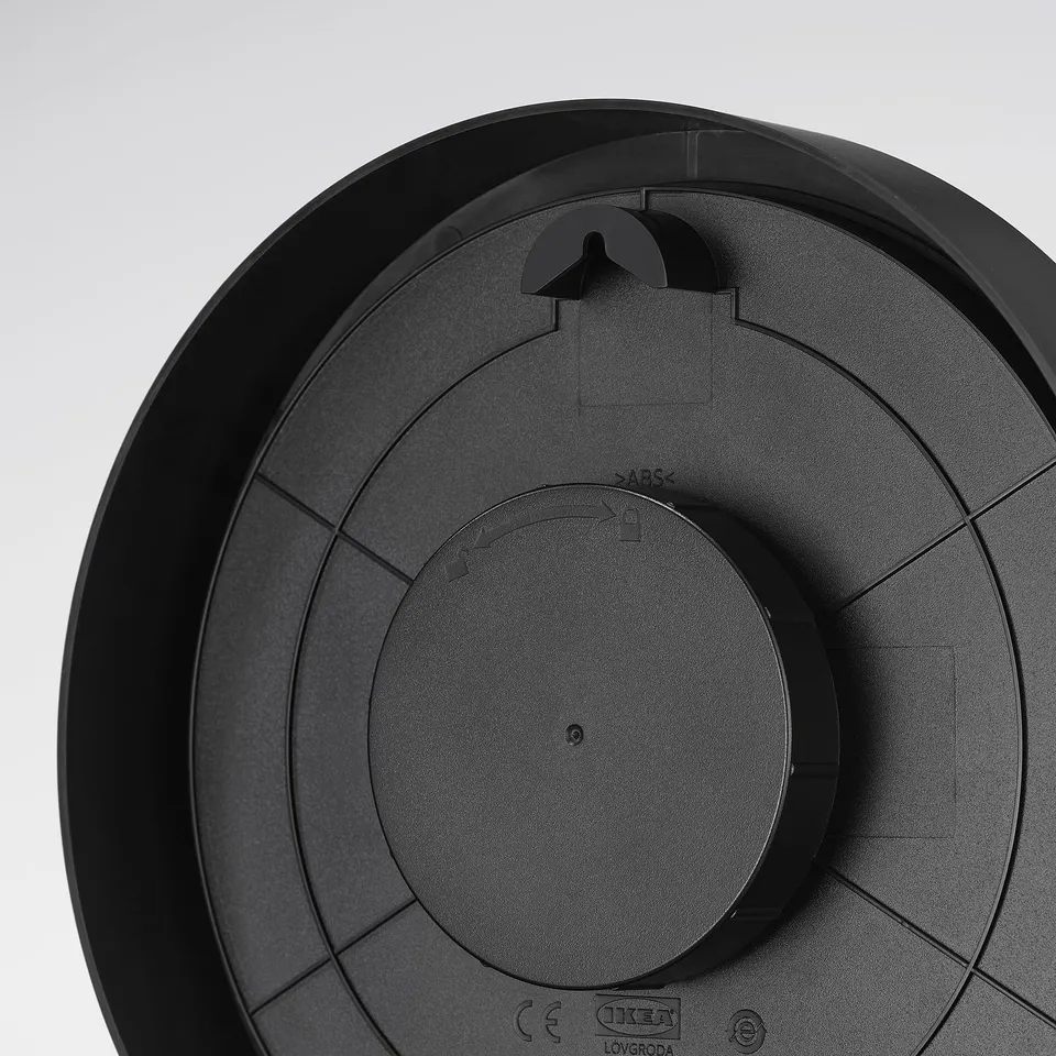 Black round clock with central dial, thick minute hand, raised hour markers, and wall mount option. Et.
