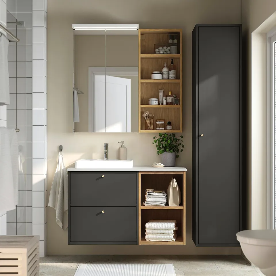 Modern bathroom setup with HAVBÄCK dark grey vanity, wooden shelves, white sink, and mirror. Compact yet functional design.