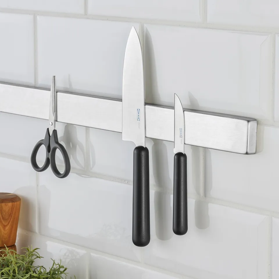 Three kitchen knives and scissors on wall magnet.