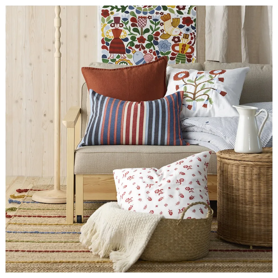 Cosy living room with RAKLEV rug, colourful pillows, jute basket, and wall tapestry.