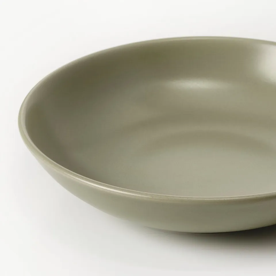 Smooth, spare dinnerware set in soft matte green, showcasing sleek design and rustic finish.