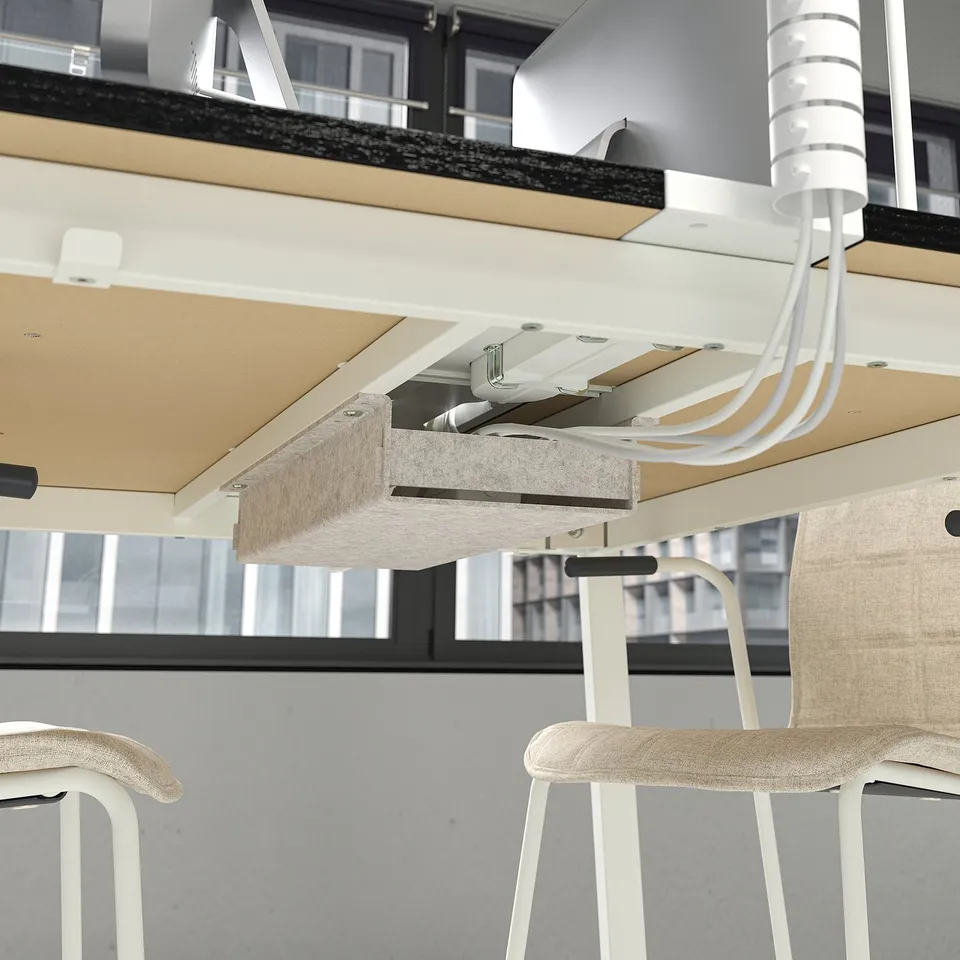Office table with footrests and cable management, designed for standing or sitting meetings.
