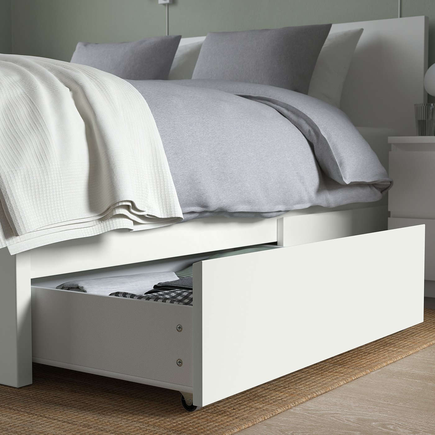 A modern bed frame with an open storage drawer under a cosy bedding set.