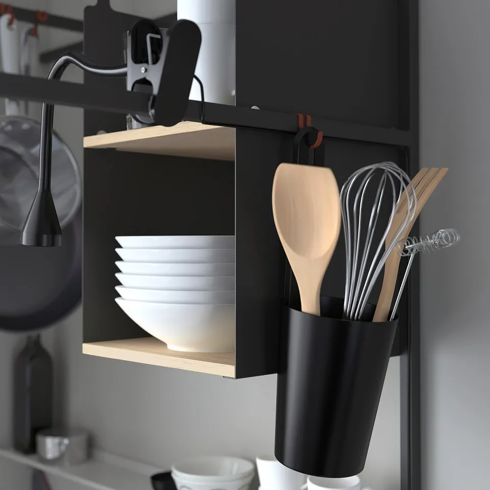 Modern kitchenette with stackable white plates and cooking utensils in hanging holder.