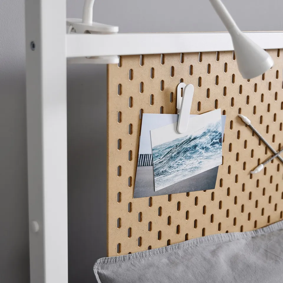 Pegboard with white clips holding waves, part of a white framed storage unit, clean and organised.