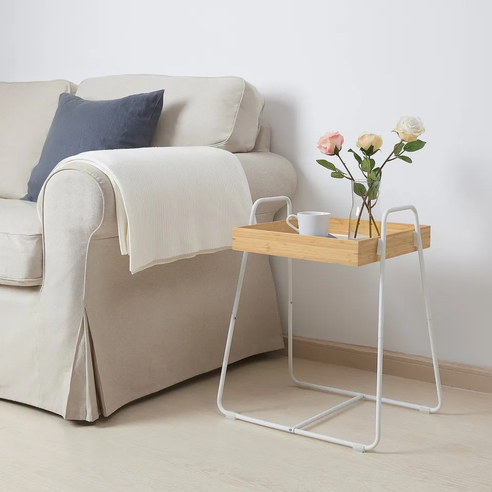 White SVENARUM side table with bamboo tray, roses, and cup next to beige couch.