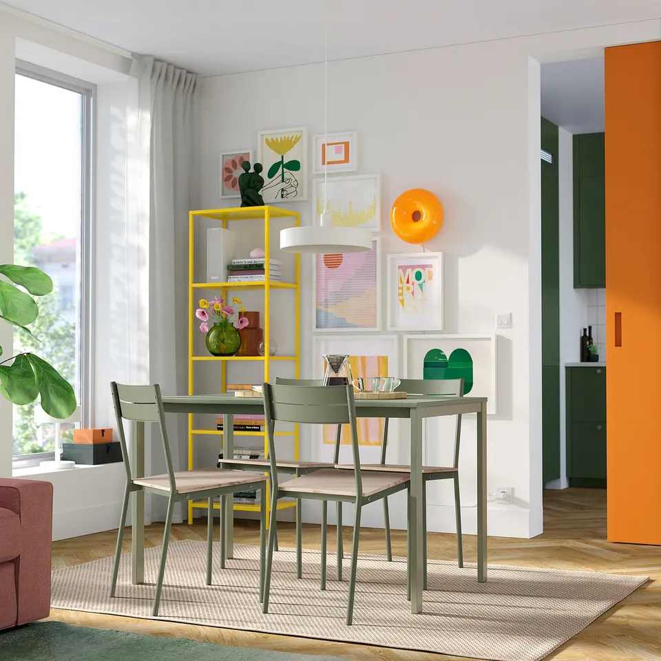 Modern dining area with yellow BUSLÄTT chairs, green seats, and metallic frames. Bright art and plants enhance the space.