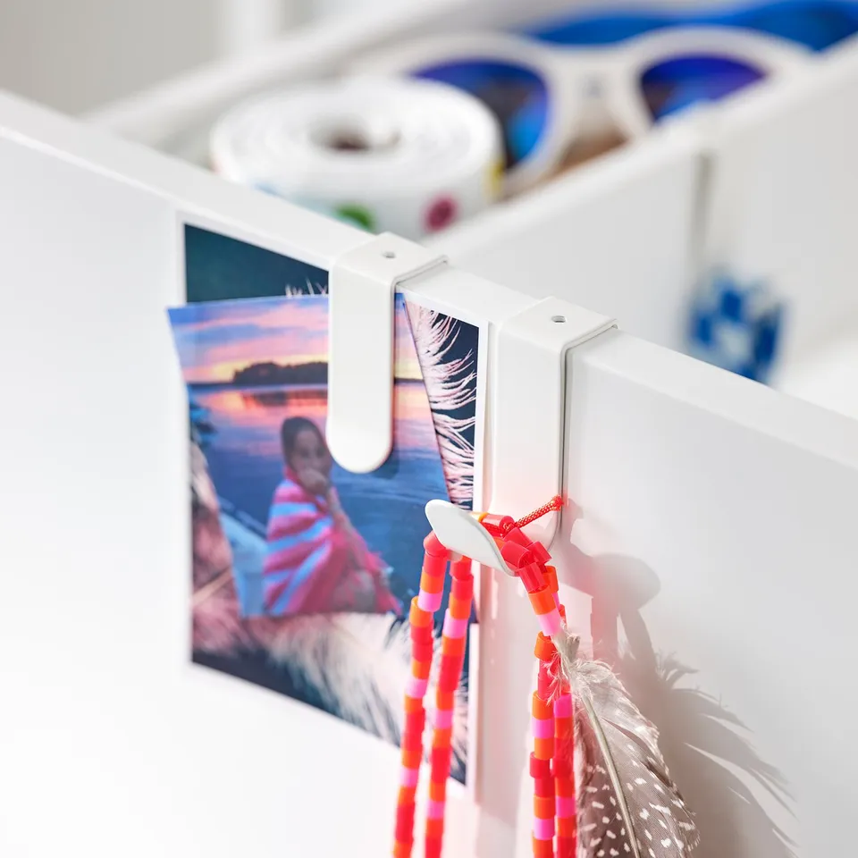 White LÄTTHET hook with colourful accessories. Bright decor item hangs on furniture.