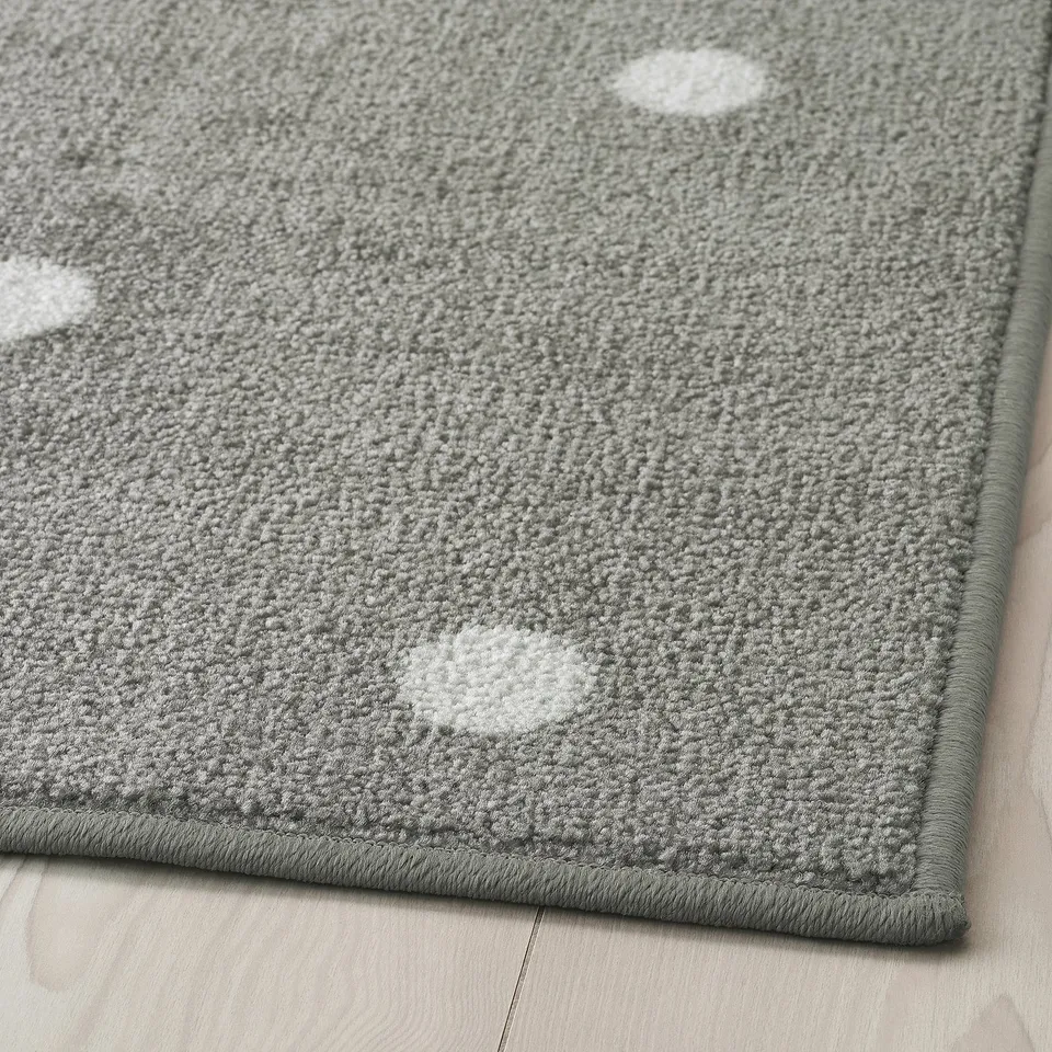 Grey area rug with white dots laid on wooden floor, showcasing its plush texture and durable edge.