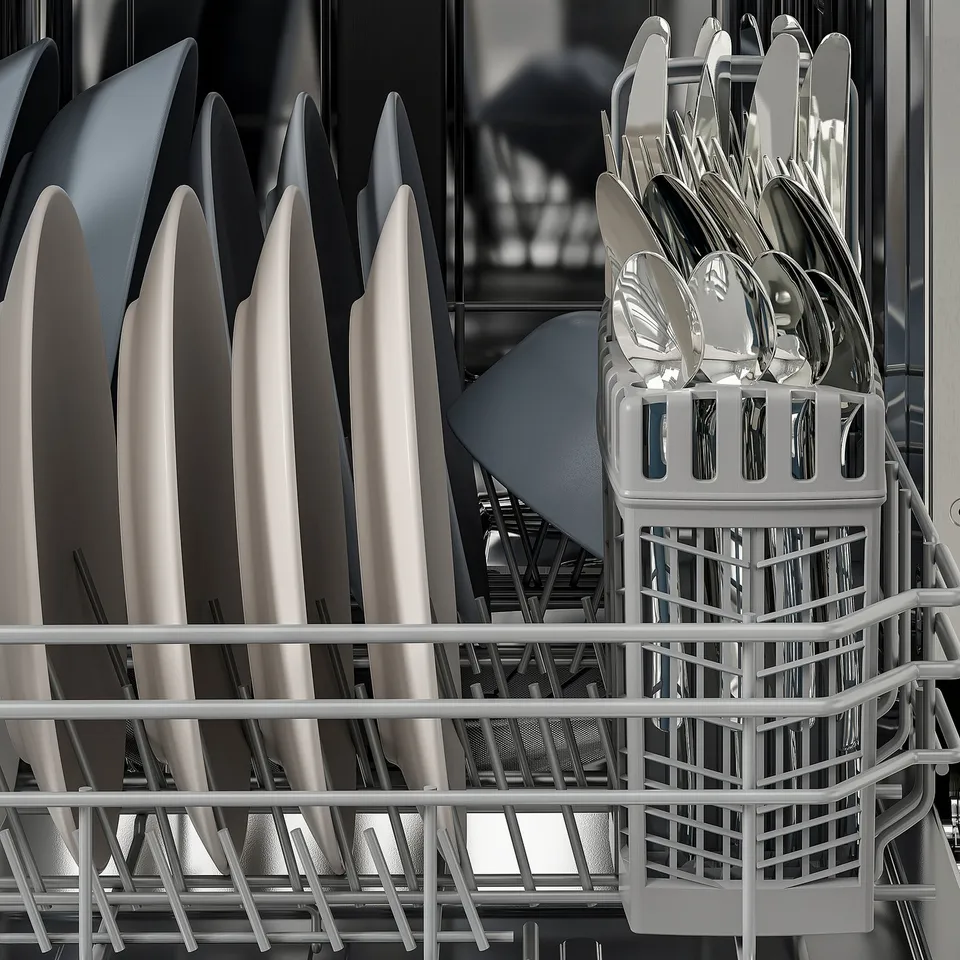 Dishwasher rack holding plates and cutlery. Plates stand upright, cutlery organised in basket.