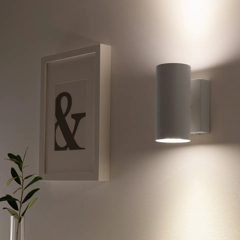 Wall-mounted light fixture with downward glow and upward light reflection.
