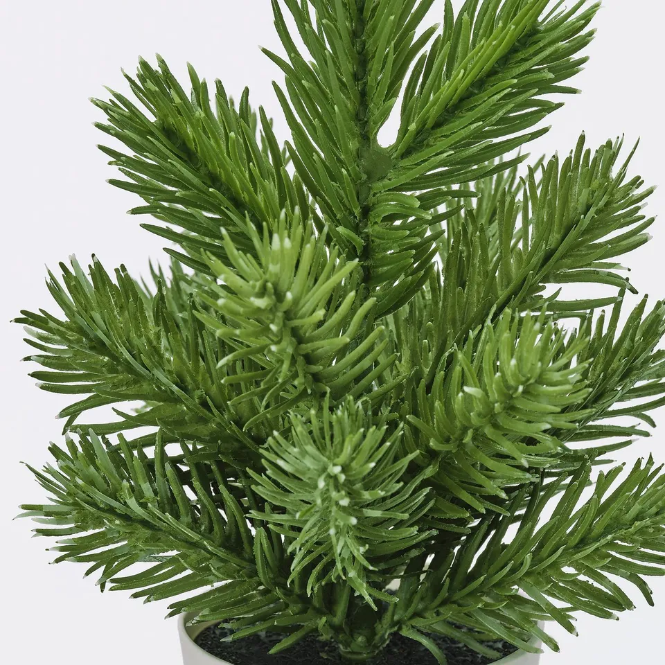 Artificial pine tree with vibrant, vibrant green needles, potted in a small container, against a white background.