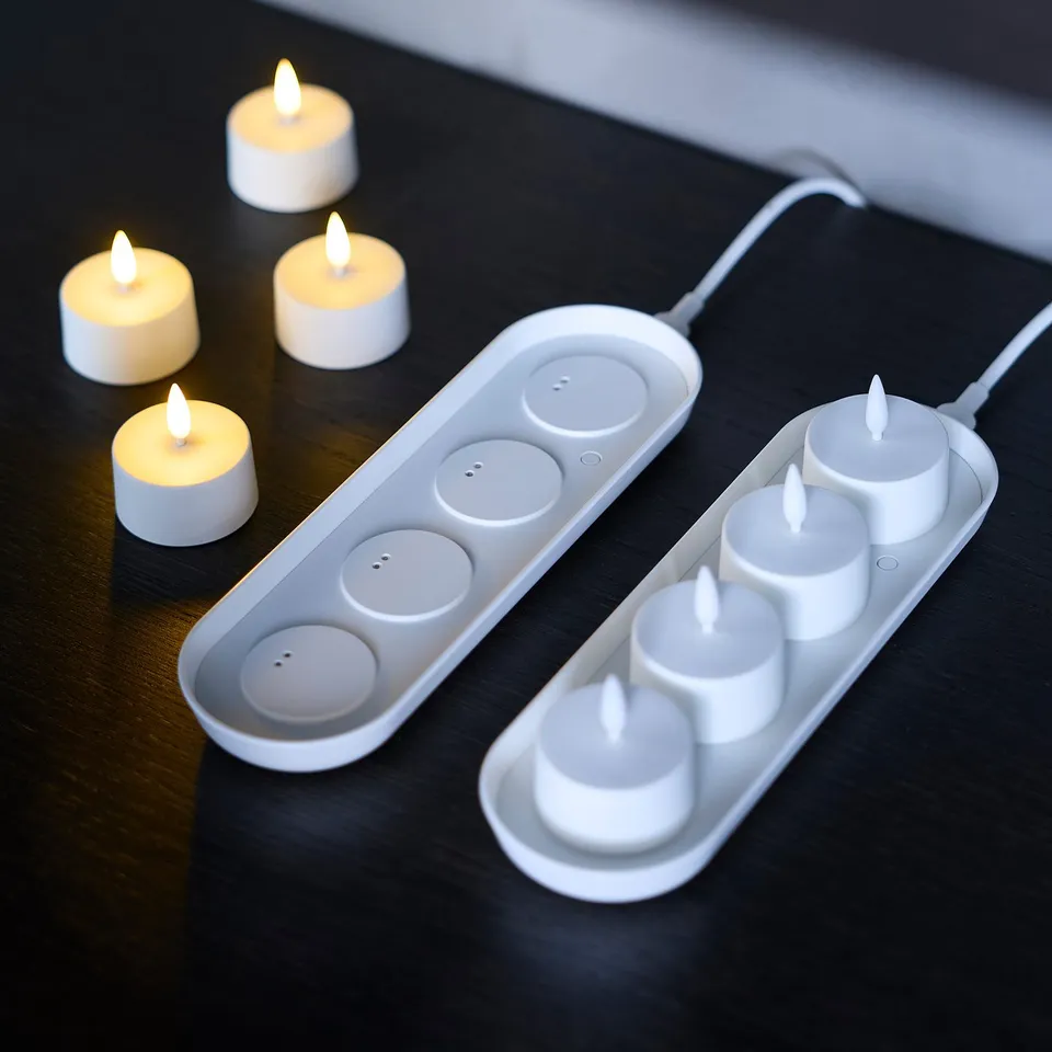 Six lit candles in two electronic trays, one charged, one not.