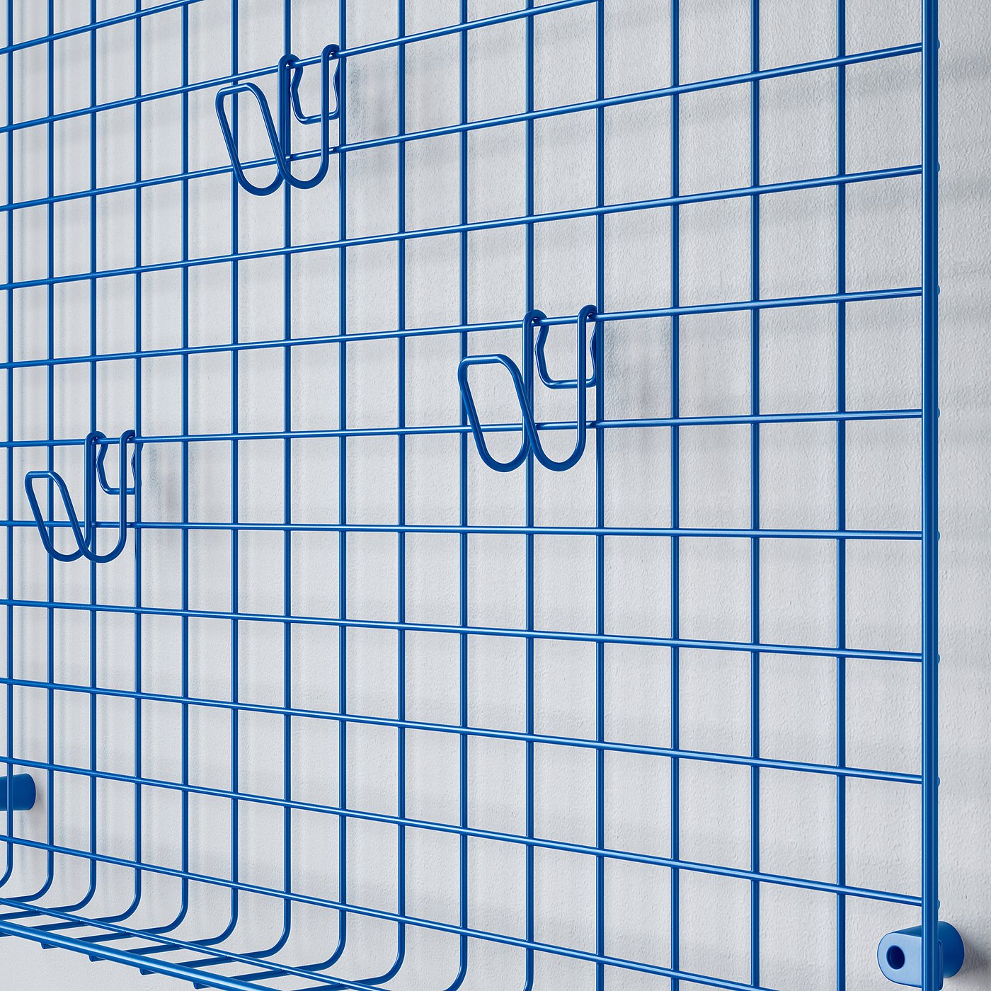 Blue wire grid wall organiser with multiple hooks, ideal for hanging items.
