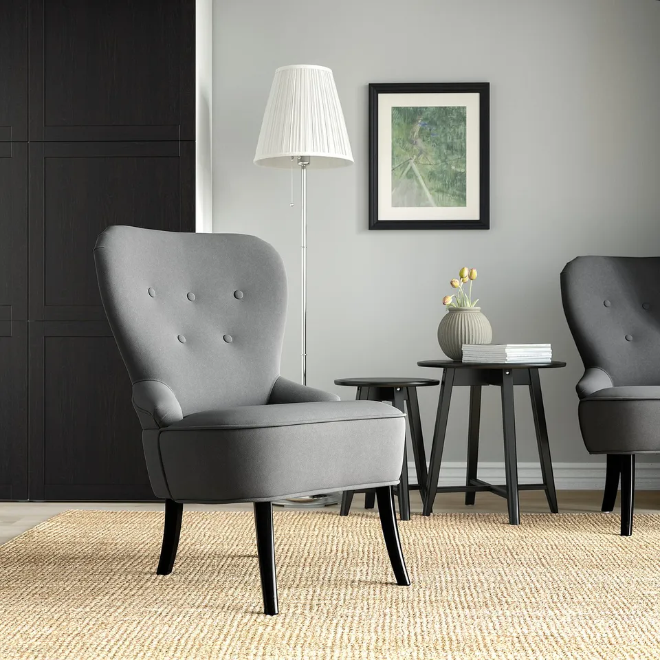 Modern living space with grey armchairs, wooden stools, lamp, and photo. Chairs traditional design, size small relative to stools.