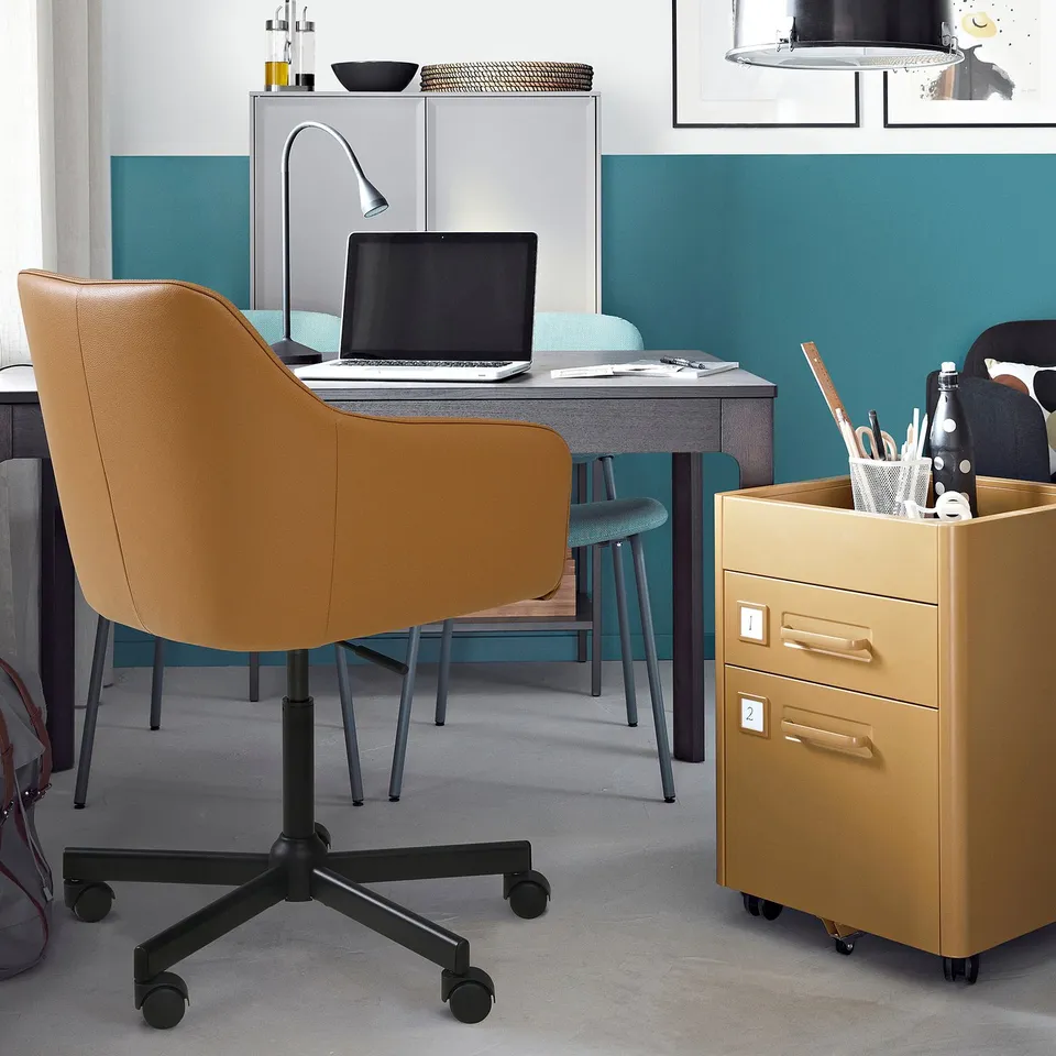 Brown leather TOSSBERG swivel chair with laptop and filing cabinet.