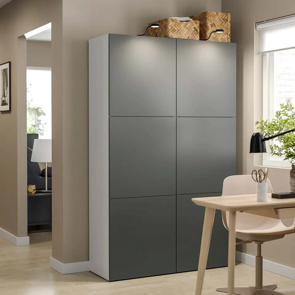 Modern room with grey BESTÅ storage unit. Top has woven baskets, bottom has wooden chair and plant.