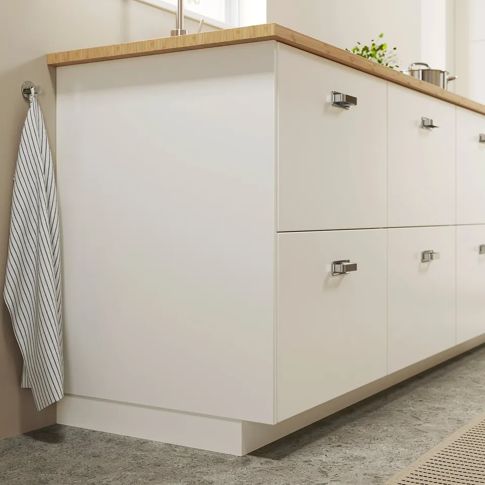 White FÖRBÄTTRA kitchen cabinet with wood top. Striped towel hangs on side.