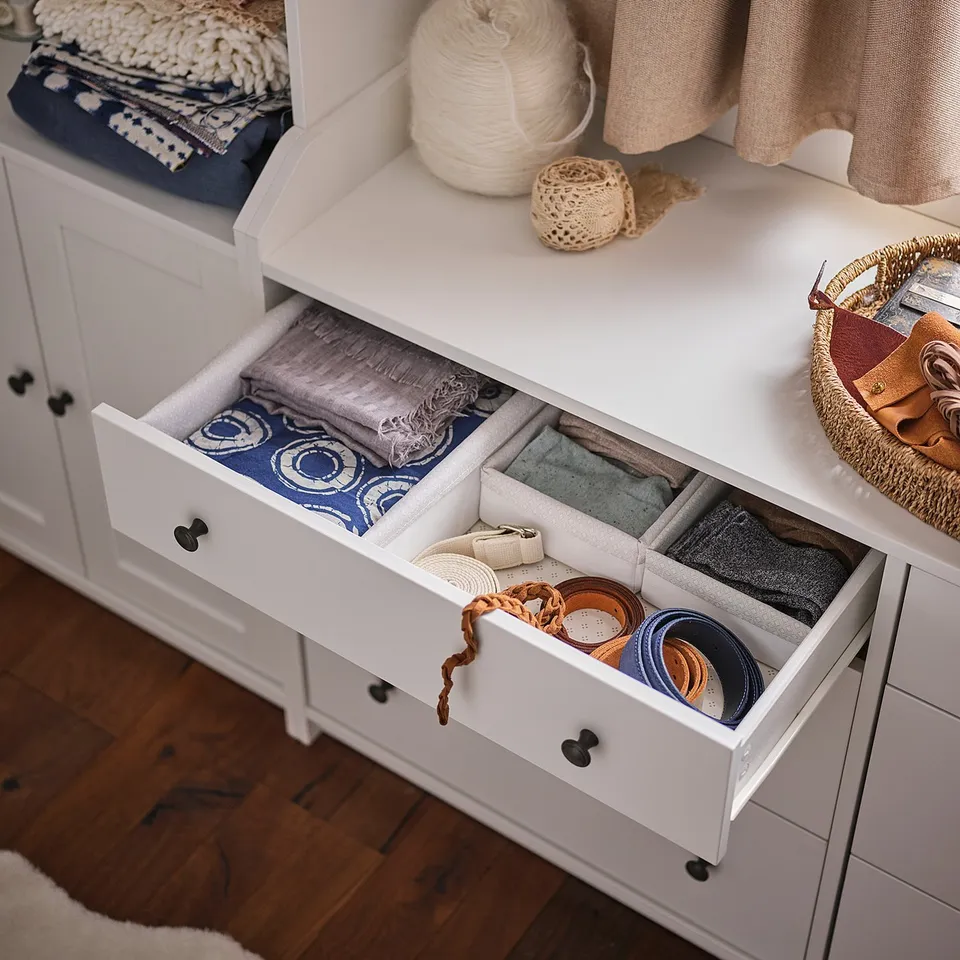 A white HAUGA storage unit with drawers and shelves. Its used for storing various textiles and craft materials.