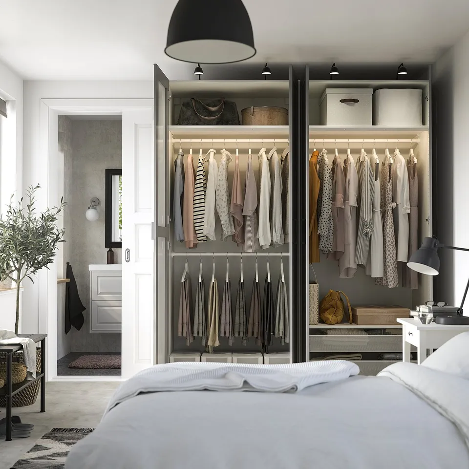 Modern bedroom with open wardrobe displaying clothes and accessories, featuring adjustable shelves, hanging space, and integrated lighting.