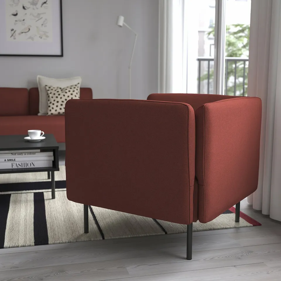 Two modern red armchairs near a window. Sofa and coffee table in the background.