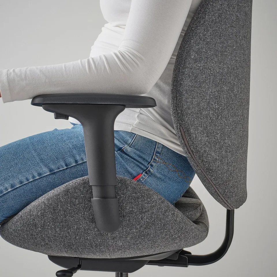 Person sitting in grey HATTEFJÄLL office chair, showing synchronised tilt mechanism in action.