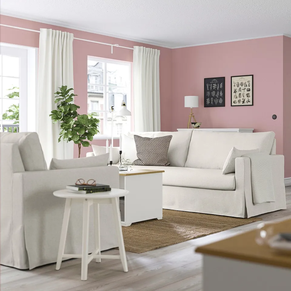 Cosy living room with pink walls, HYLTARP sofa, and decor.