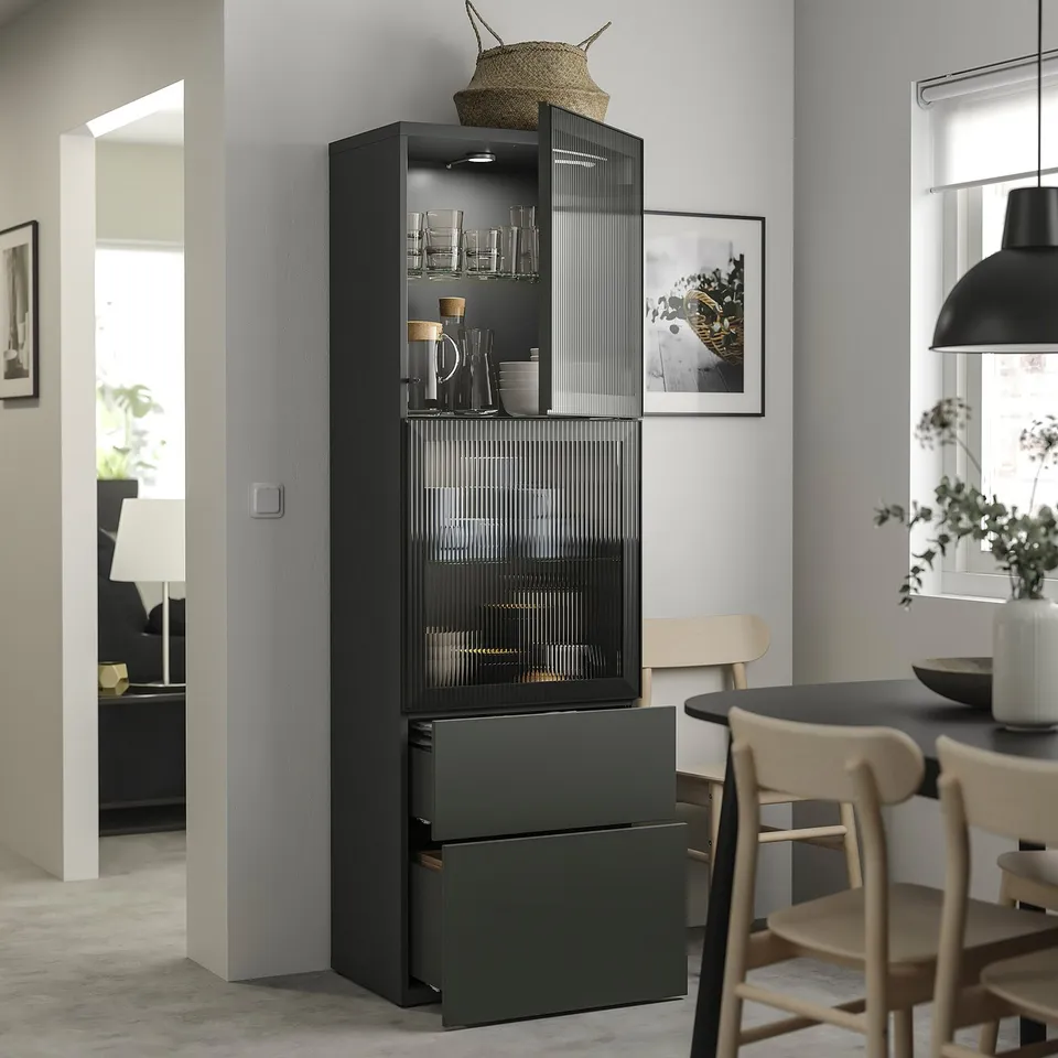 Modern black glass display cabinet with wooden top, storing glasses, and jars. Positioned between a dining area and a living room.