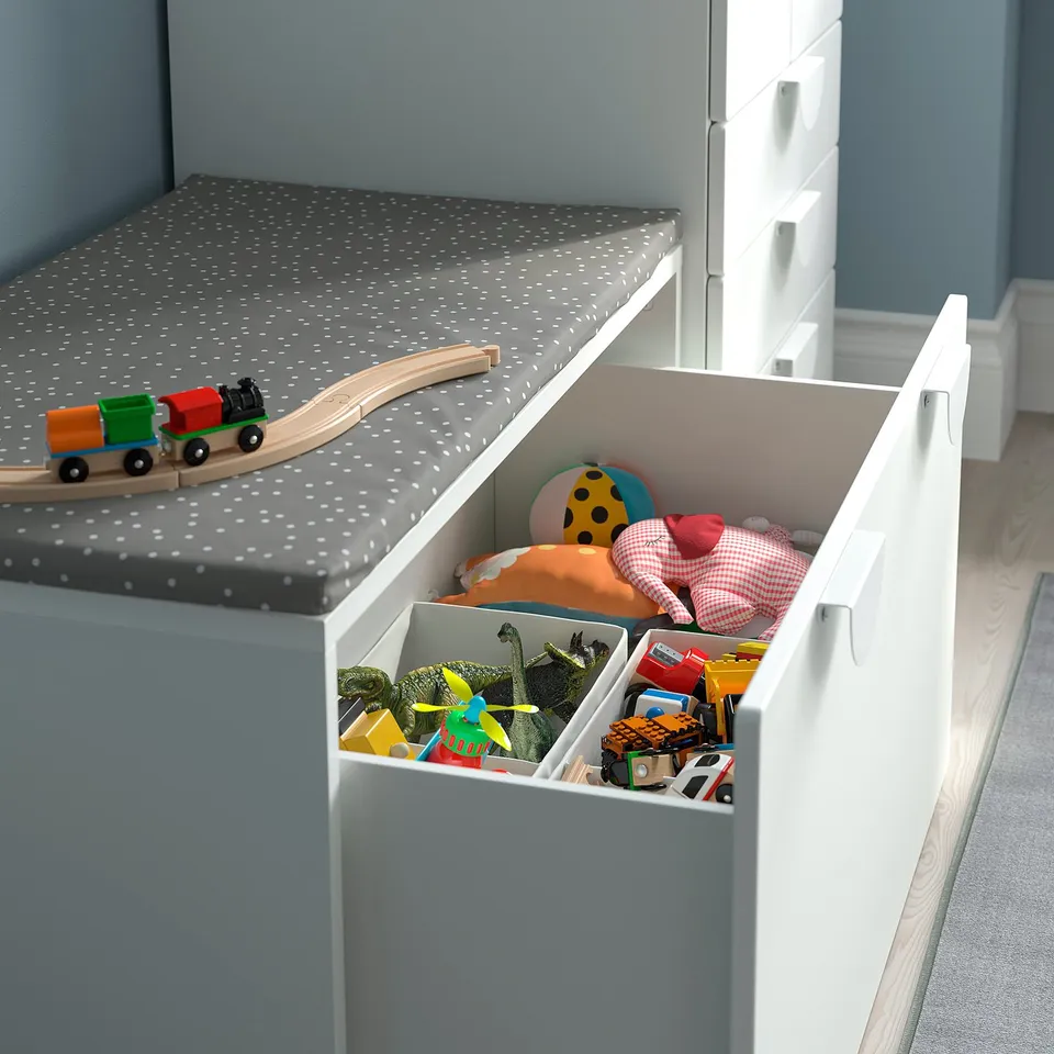 White storage unit with open drawer showing toys, including a toy train on top. Good for tidying up.