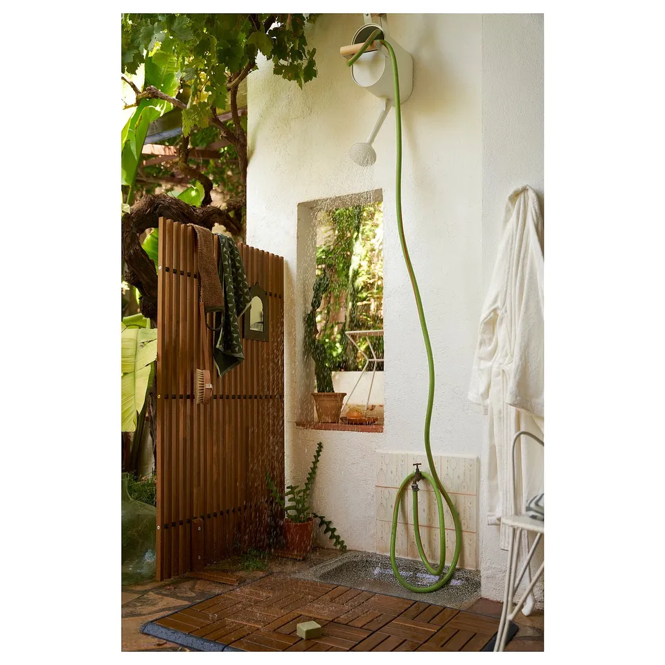 Outdoor living space with green hose and white towel on wall-mounted holder.