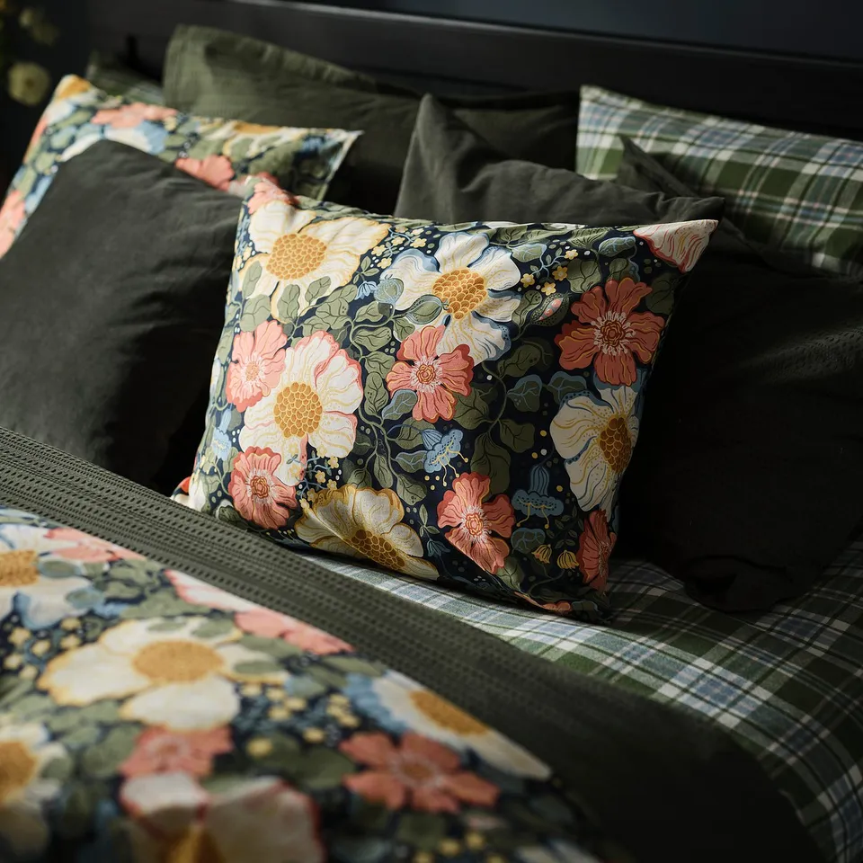 Floral-patterned pillow on plush bedding, soft fabric feels luxurious.