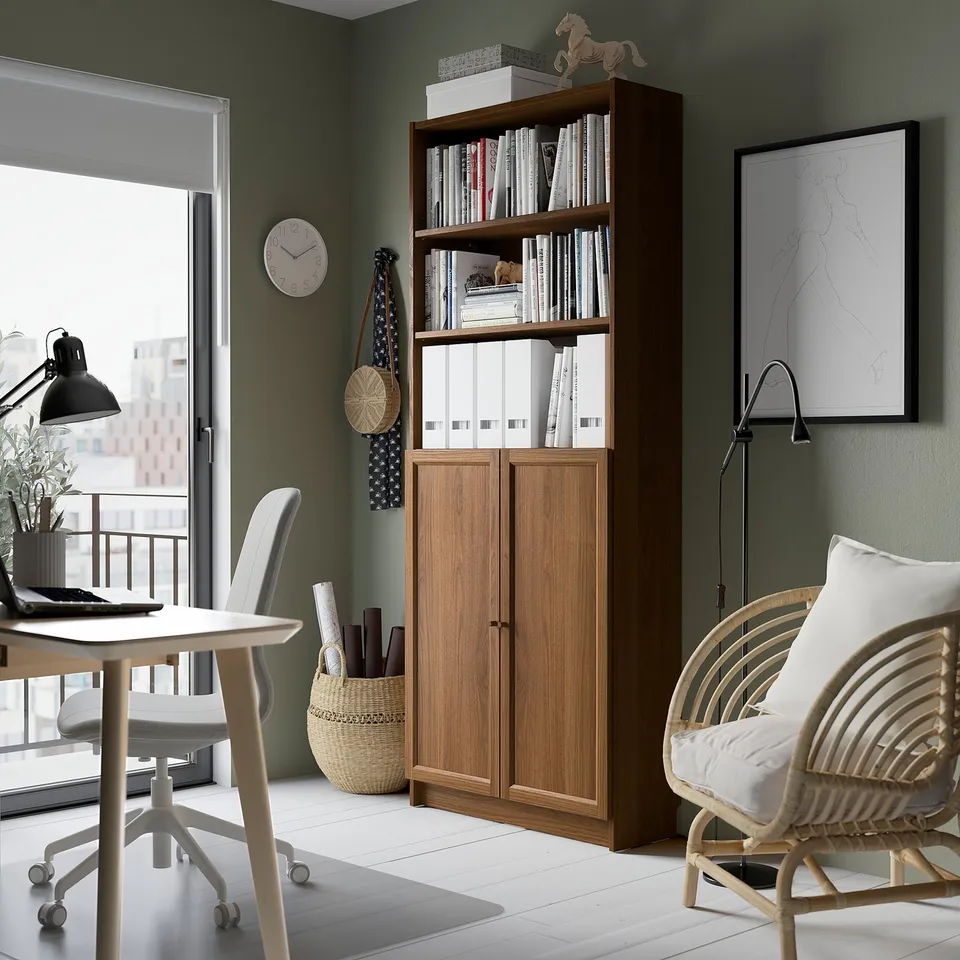 Home office with BILLY bookcase, desk, chair, lamp, clock, and map.