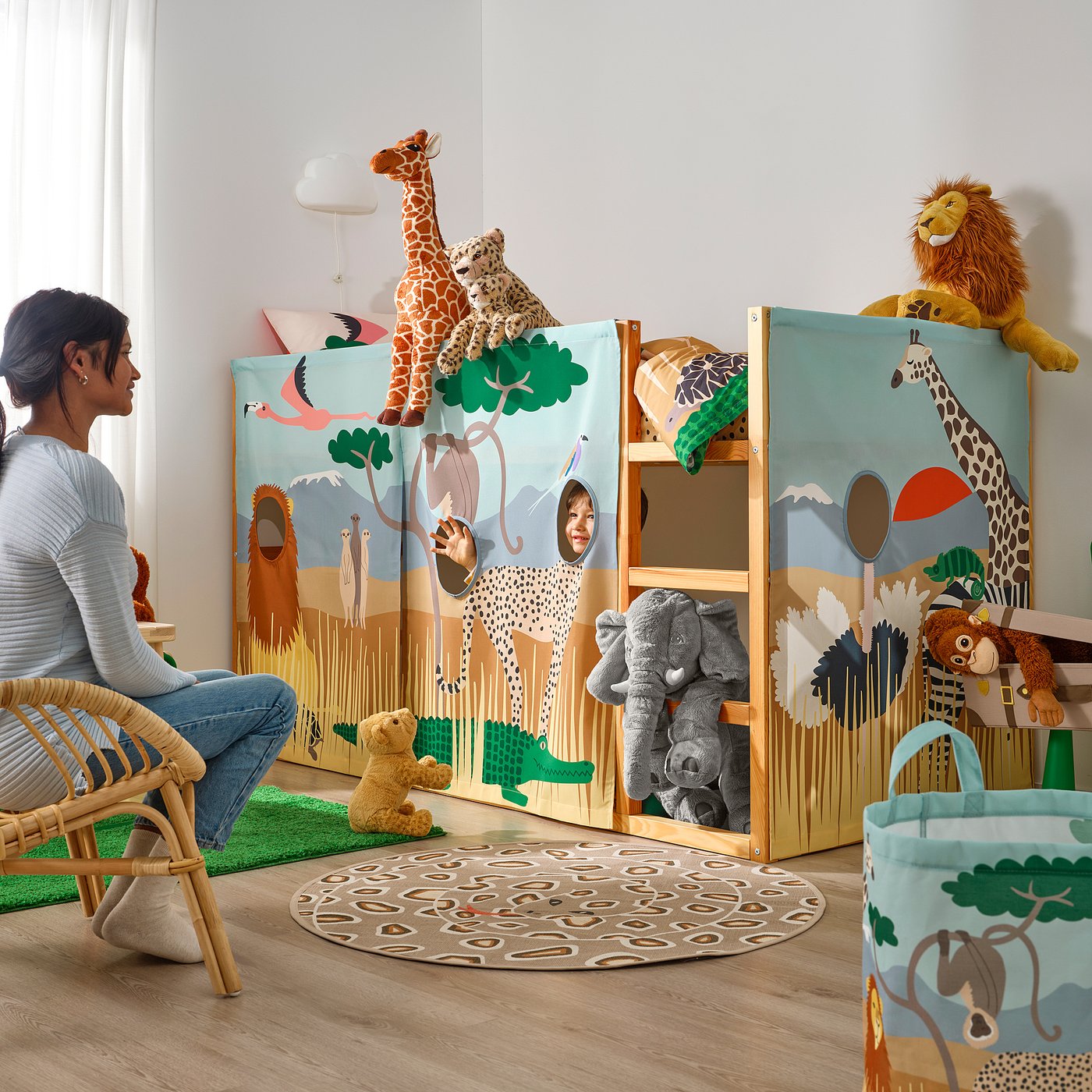 Person in kids room with KURA bed, savannah-themed curtain conceals playing child.