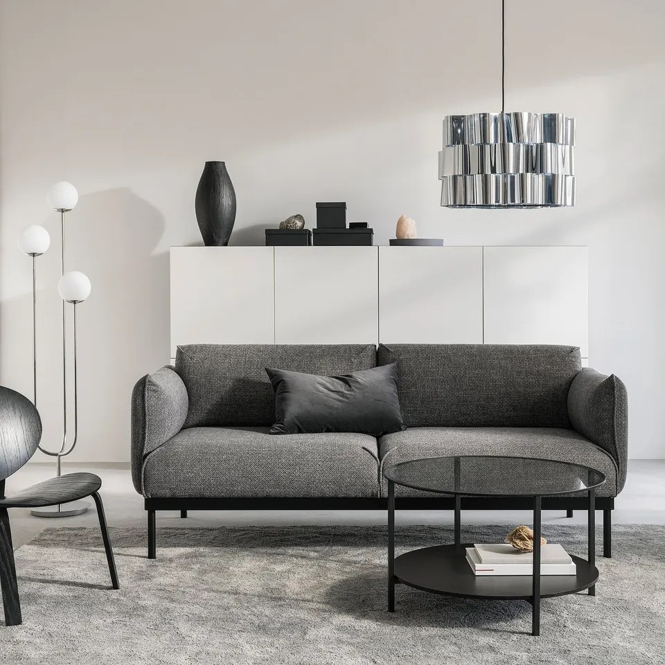 Modern living room a grey ÄPPLARYD sofa with black accents, a white cabinet, and sleek lighting.