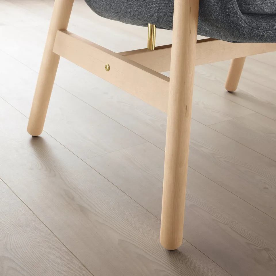 Modern light wood chair with sleek, curved design and grey seat, positioned on light hardwood floor.