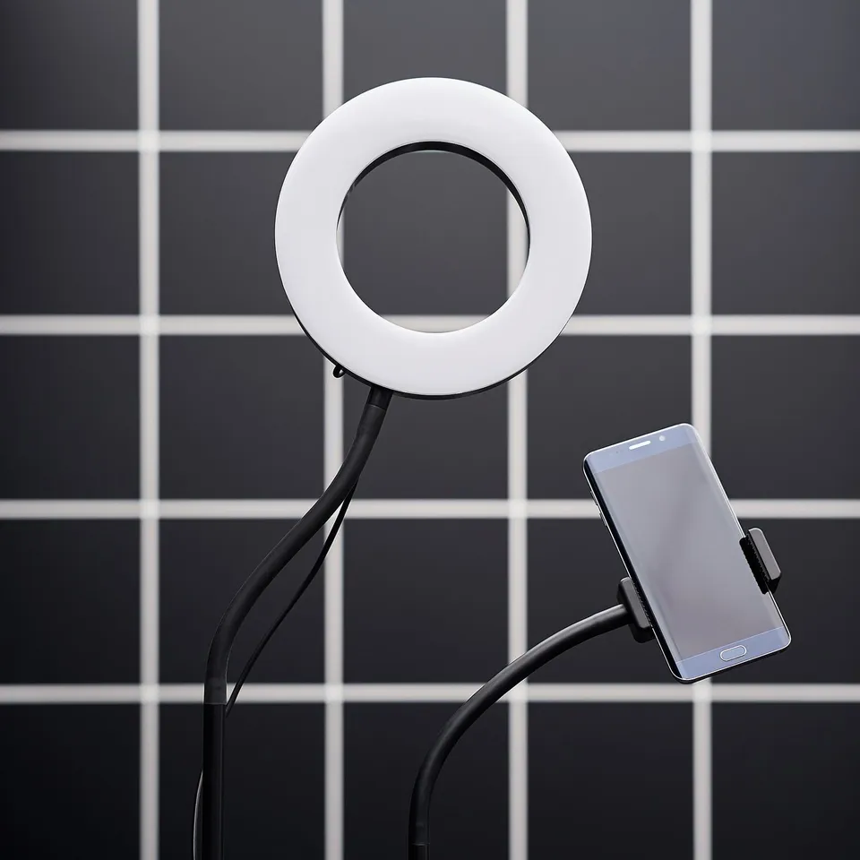 A black and white lånespela ring light with adjustable phone holder for video streaming.
