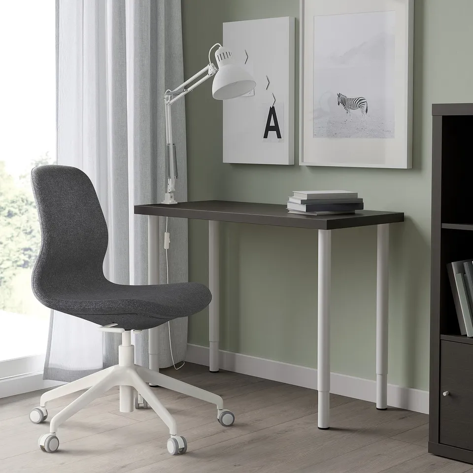 Modern black desk with grey chair, silver legs, zebra poster, lamp, storage.