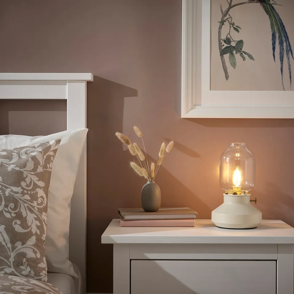 Cosy bedroom corner with TÄRNABY lamp, dried flowers, and floral pillow.