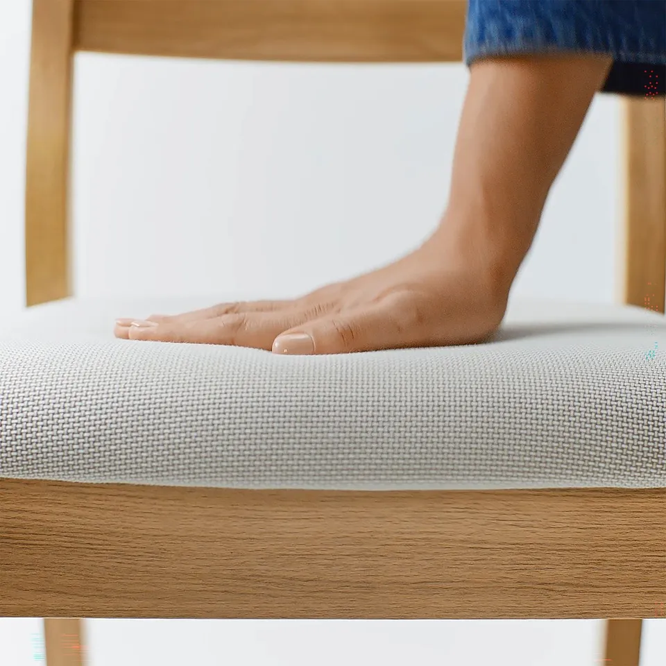 A persons foot touches a soft, textured cushion on a sturdy wooden table, indicating high-quality comfort and durability.