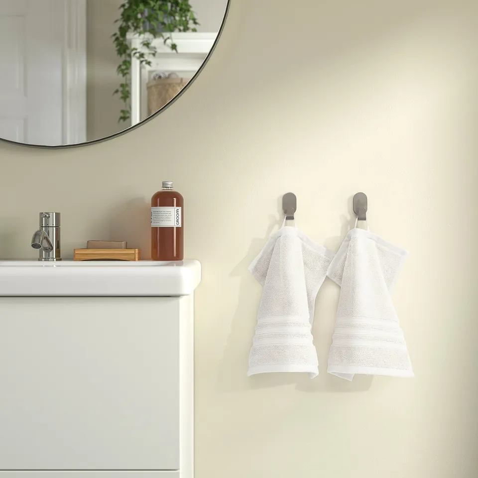 Modern bathroom: two white towels on hooks beside small vanity with mirror.