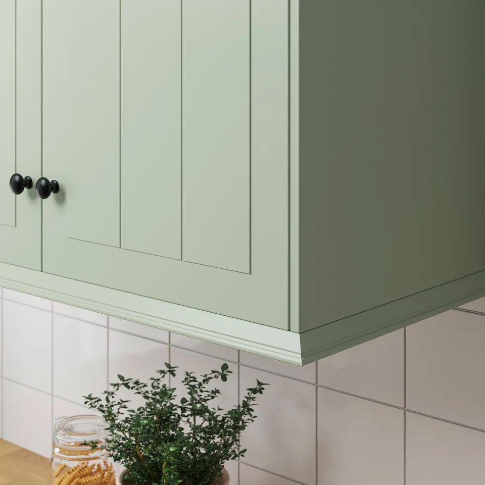 Green cabinets, black knobs, white tiles, under-cabinet lighting.