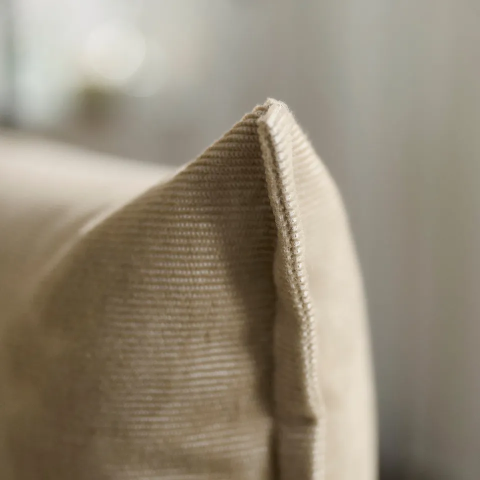 Close-up of beige fabric, showcasing soft, textured weave and neat stitching.