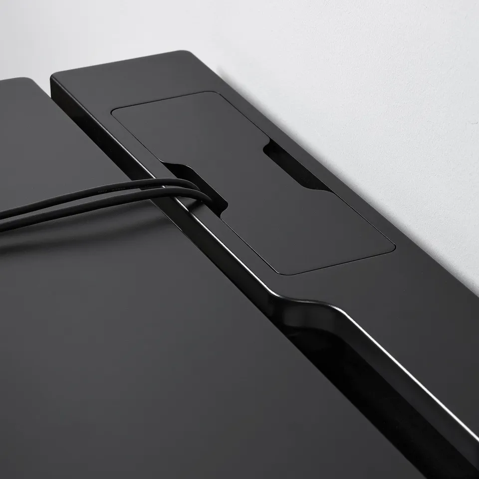 Modern black gaming desk close-up, sleek and durable design with cable management slot.